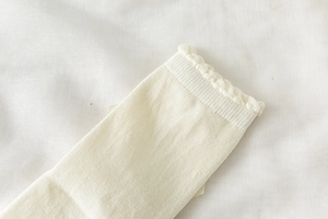 Détail macro des chaussettes en tricot crème avec bordures à volants et dentelle douce