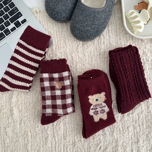 Detailed view of four pairs of warm burgundy wool socks with bear embroidery and stripes