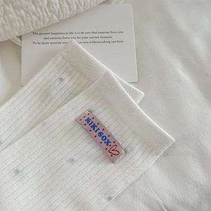 Détail de chaussettes côtelées blanc crème avec motif floral bleu et étiquette cousue