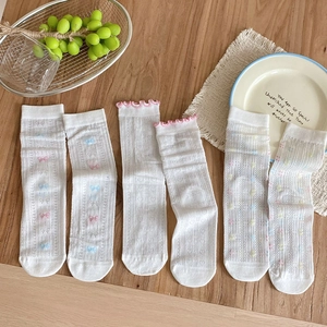 Close-up of white mesh mid-calf socks with delicate pink bows and ruffled edges