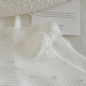 Gros plan de chaussettes en maille côtelée blanche à pois bleu clair et texture douce