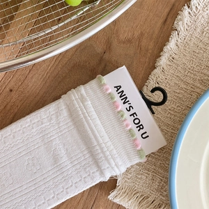 Close-up of white mesh socks with delicate knit texture and pink ruffled lace trim