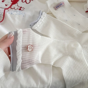 Gros plan de chaussettes blanches côtelées avec bord ondulé lilas et broderie pomme