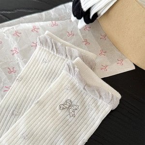 Detailed macro view of white ribbed socks featuring silver bow embroidery and grey frilled cuffs