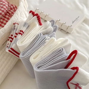 Détail du tissu tricoté des chaussettes blanches et grises avec des nœuds rouges doux