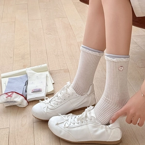 Détail de chaussettes en maille côtelée avec bords festonnés et broderie pomme rouge