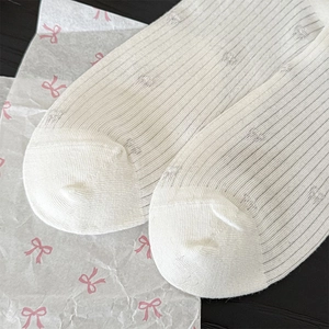 Detail of white mesh socks with bow patterns and ribbed texture on black background