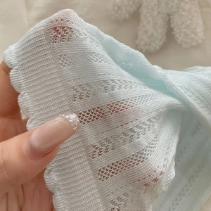 Close-up of mint blue hollow knit fabric showing breathable texture and soft mesh detail