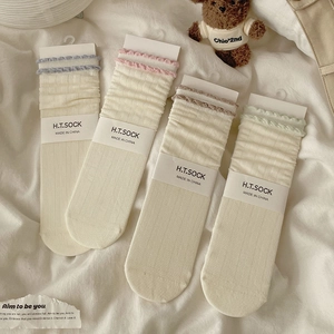 Close-up of four pairs of off-white ribbed socks with colorful lettuce-edge trims