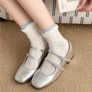 Macro shot of silver metallic double-buckle Mary Janes with white lace floral socks