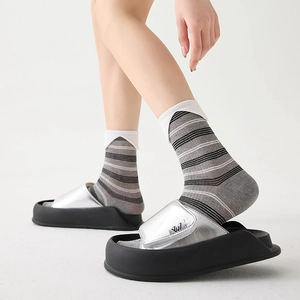 Detail of silver metallic platform wedge slide sandals with logo on a sleek black sole