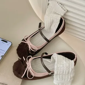 Close-up of brown suede Mary Jane flats with pink trim and white ruffled socks