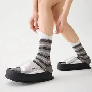 Close-up of silver metallic platform slide sandal worn with striped crew socks