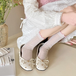 Close-up of white lace mesh socks with pink ruffle edge and bow accent shoes