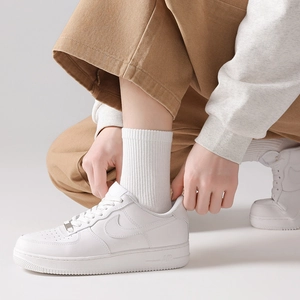 Close-up of low-top white leather sneakers with sports socks and brown trousers