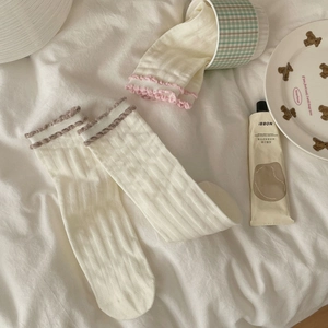 Detail of white ribbed crew socks featuring pink and coffee contrast ruffled edge trim