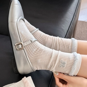 Close-up of cream ribbed socks with bear embroidery and silver Mary Jane shoes