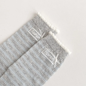 Close-up of gray striped socks with white lace trim, ribbon bow, and Fashion embroidery
