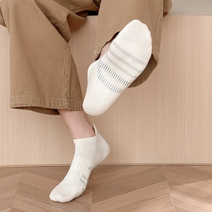 Close-up of white breathable mesh low-cut socks with grey stripes on a wooden floor