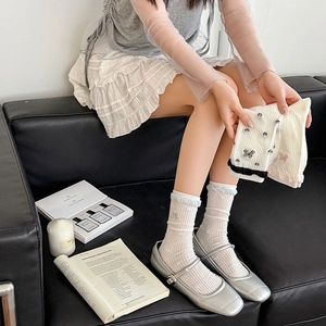 Detail of white ribbed crew socks with light blue ruffle edge and butterfly embroidery