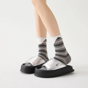 Silver metallic platform sandals with wide strap and thick black sole worn with socks