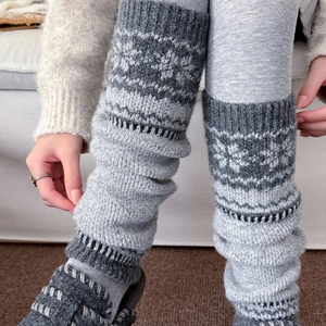 Close-up of gray knitted leg warmers with Nordic snowflake pattern and ribbed elastic cuffs