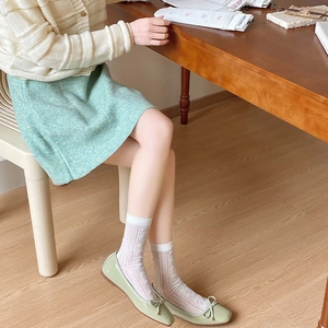 Close-up of light green patent leather ballet flats with cute bow and white mesh lace socks