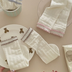 Close-up of white ribbed socks with colorful ruffled edges in a warm cozy setting