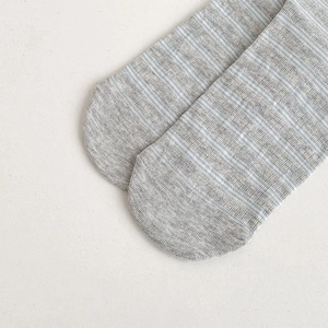 Close-up of knit cotton socks showing grey striped texture and fine toe stitching detail