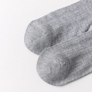 Macro shot of grey knitted mid-calf socks showing seamless toe seam and fabric texture