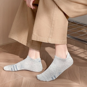 Detail view of grey low-cut sports socks with blue stripes and breathable mesh on a model