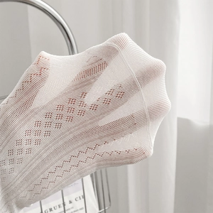 Close-up of white hollow mesh socks showing delicate diamond patterns and elastic texture