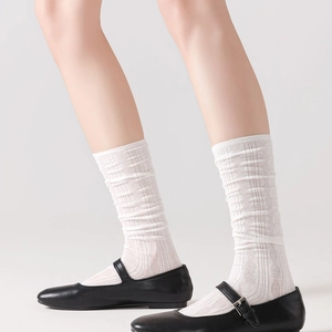 Detail of white ribbed crew socks with vertical knit pattern worn with Mary Jane shoes