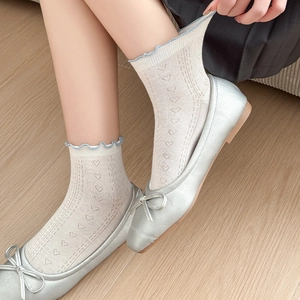 Detail of white mesh socks with heart cutouts and blue ruffle trim on ballet flat shoes
