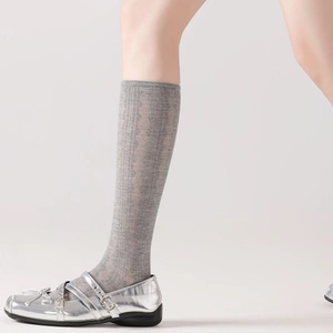 Close-up of grey knit calf socks with diamond patterns and silver Mary Jane shoes
