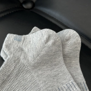 Close-up of grey breathable mesh socks with blue striped cuffs on a black background