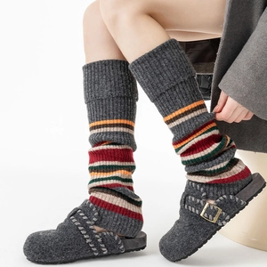 Detail of grey knitted leg warmers with colorful stripes and cozy felt slippers