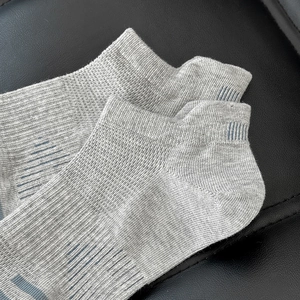 Detail of gray low-cut socks with ribbed texture and blue anti-slip heel stripes
