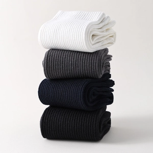 Vertical stack of four pairs of ribbed mid-calf socks in white, gray, navy, and black