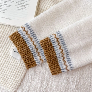 Detailed close-up of knit sweater cuffs featuring blue and brown wavy patterns
