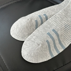 Close-up of grey knit socks featuring triple blue stripes on the seamless toe area