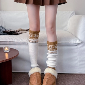 Detail of white knitted leg warmers with vintage brown snowflake patterns and ribbed cuffs