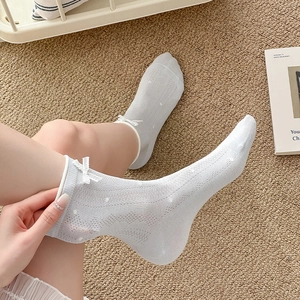 Detail of grey hollow knit socks featuring a delicate white ribbon bow and lace edges