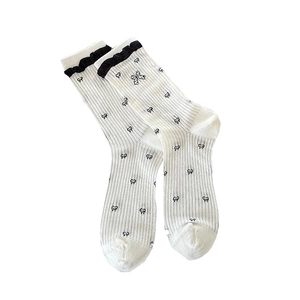 White Japanese Lolita crew socks with black ruffled edges and bow patterns