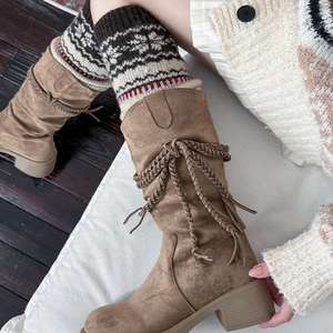 Detail of vintage patterned knit leg warmers paired with brown tassel suede boots