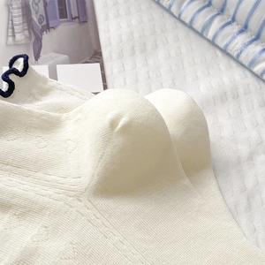 Close-up of white heart cutout socks with blue wavy edges and ribbed knit texture