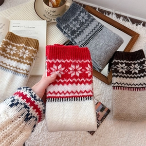 Detail of Nordic snowflake pattern on thick knit leg warmers with ribbed cuffs