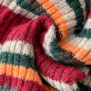 Detailed close-up of thick striped knit fabric showing texture and mixed yarn colors
