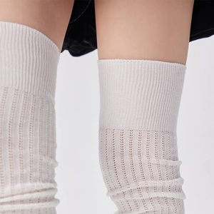 Close-up of white breathable hollow knit pattern and ribbed cuff on knee-high socks