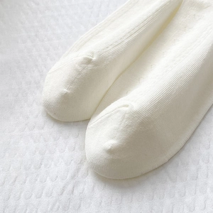 Close-up of white knit mesh socks with heart cutouts and smooth flat toe seams